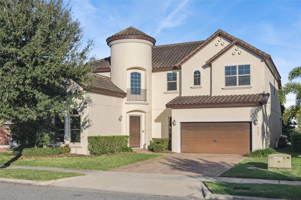 A two-story stucco house with a turret, tile roof, and attached two-car garage — 9207 BUSACO PARK WAY, WINTER GARDEN, FL