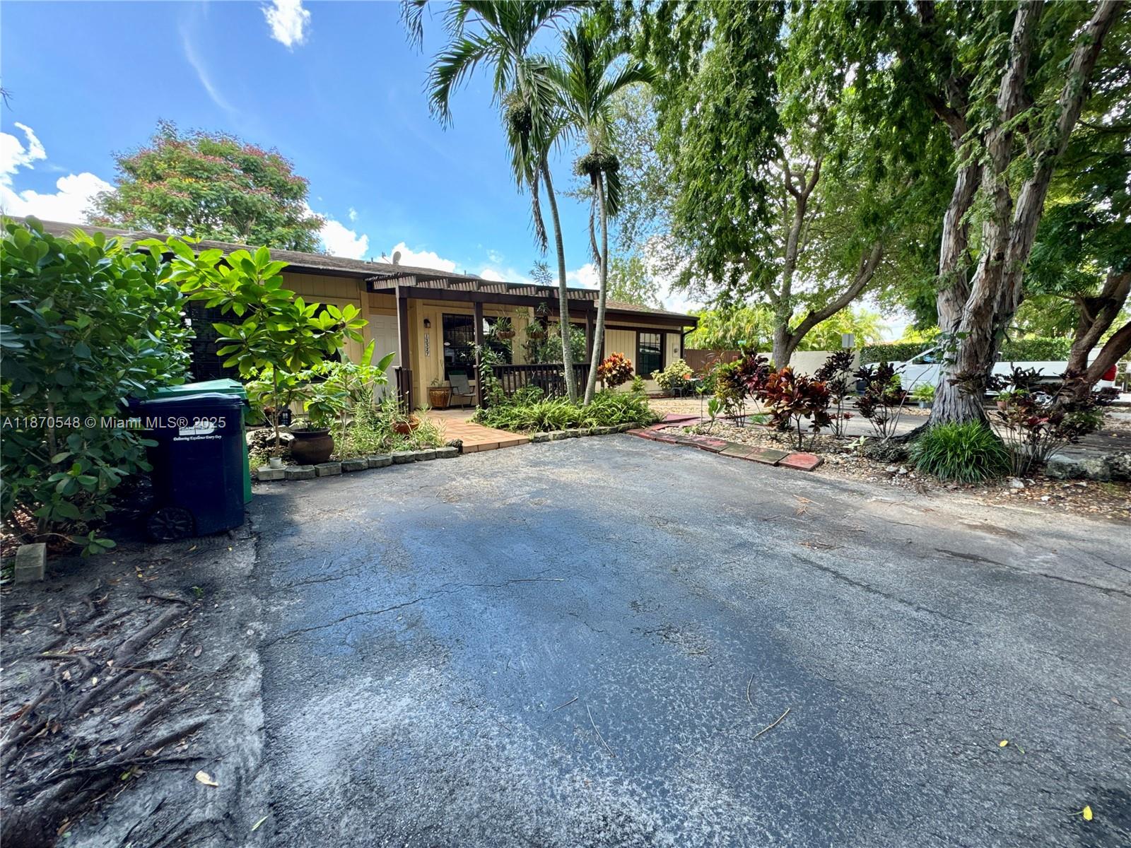 A single-story house with a paved driveway, palm trees, and a wooden porch entrance — 13527 SW 101st Ln, Miami FL 33186, MIAMI, FL