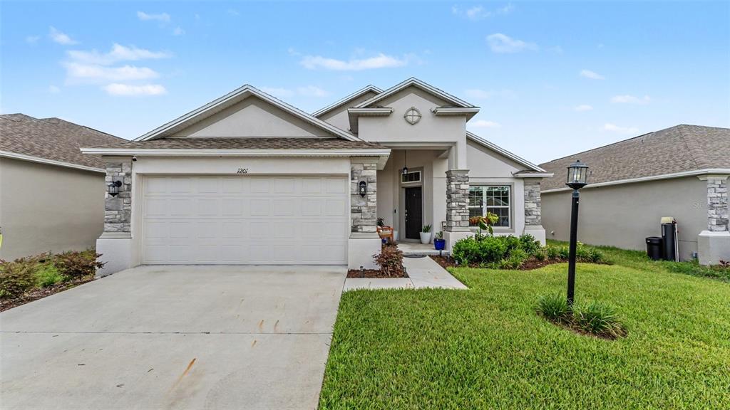 A single-story house features a two-car garage, stone accents, and a covered front entryway — 1201 PINTAIL PLACE, LAKELAND, FL