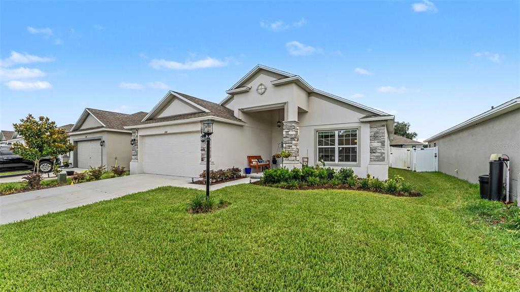 A single-story suburban house features a two-car garage, stone accents, and a front lawn — 1201 PINTAIL PLACE, LAKELAND, FL
