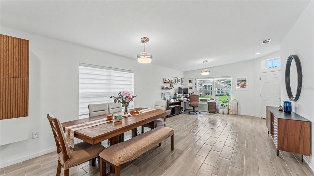 A dining area with a wooden table and bench features light tile flooring and an office — 1201 PINTAIL PLACE, LAKELAND, FL