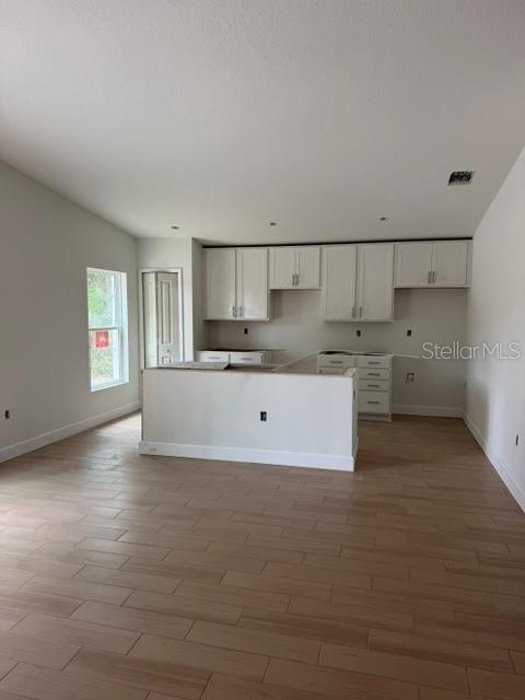 An open-concept living area features light wood-look tile flooring and a view of the kitchen — 3038 THORNHILL ROAD, WINTER HAVEN, FL