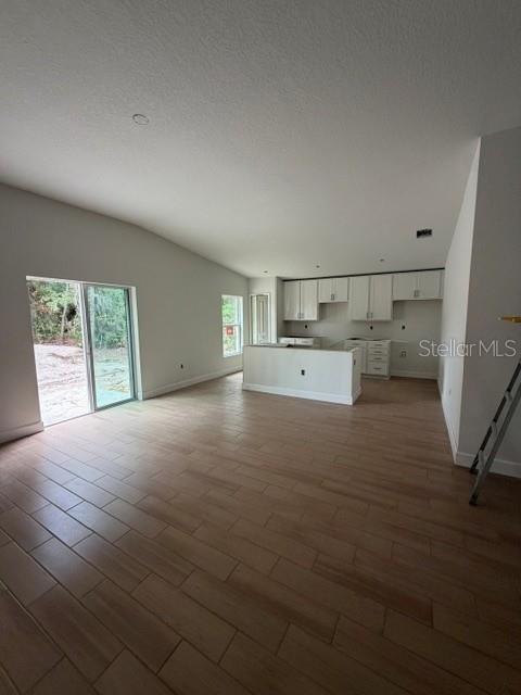 A kitchen with white cabinets and a center island opens into a spacious living area — 3038 THORNHILL ROAD, WINTER HAVEN, FL