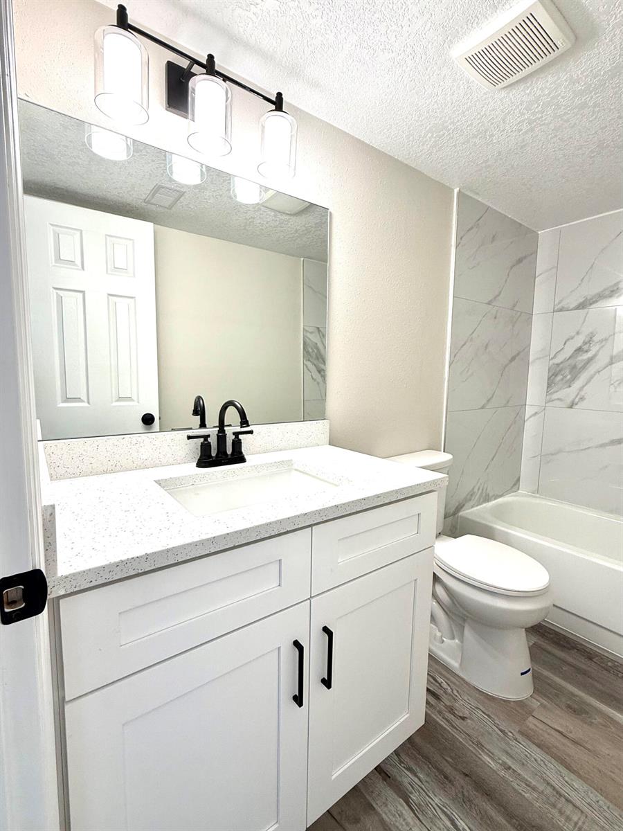 A bathroom features a white vanity with a speckled countertop, black fixtures, and a tub — 1465 NW 43rd Avenue, Okeechobee FL 34972, OKEECHOBEE, FL