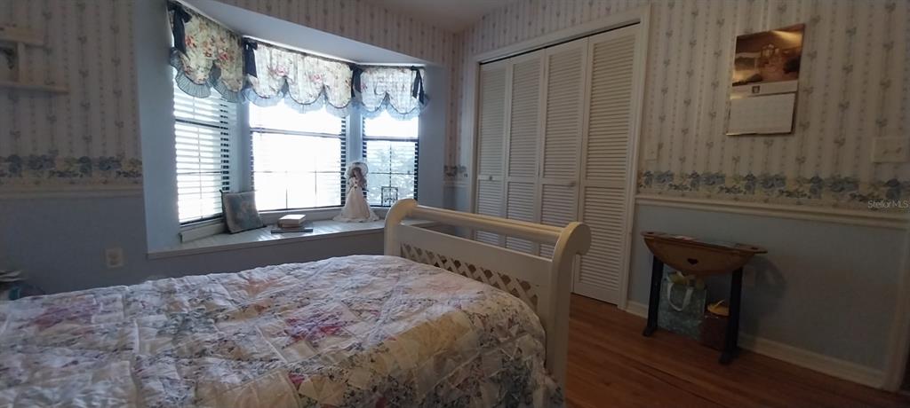 A bedroom features a bay window with a seat, a white bed frame, and wallpaper — 8943 SILVER LAKE DRIVE, LEESBURG, FL