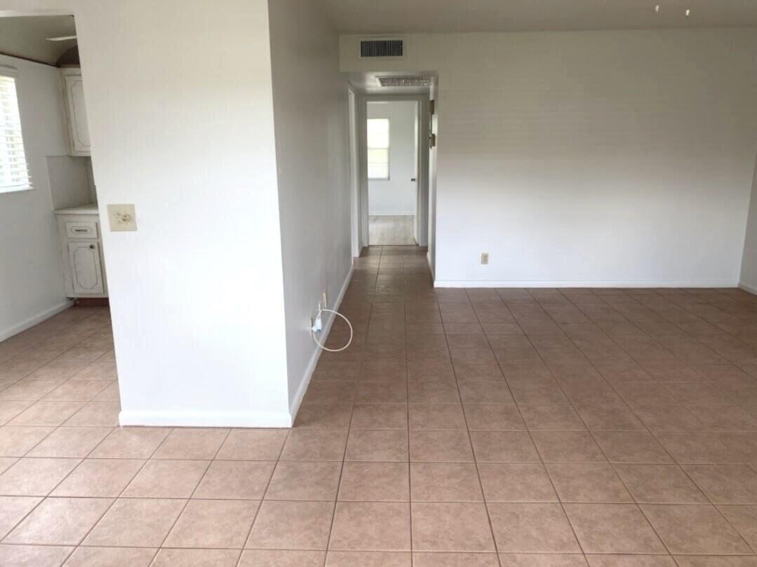 An interior view showing a tiled floor, white walls, and a hallway leading to another room — 99 Mansfield C # 99, Boca Raton FL 33434, BOCA RATON, FL