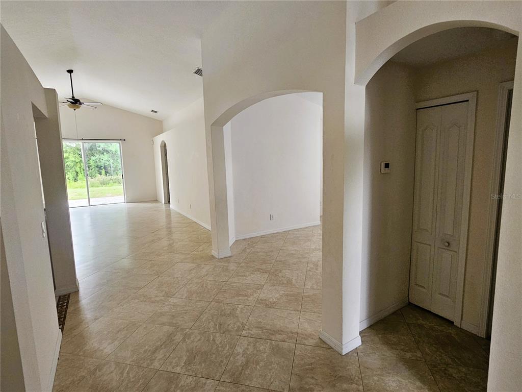 An interior view shows a tiled living area with arched doorways and a sliding glass door — 3220 CLOVER BLOSSOM CIRCLE, LAND O LAKES, FL