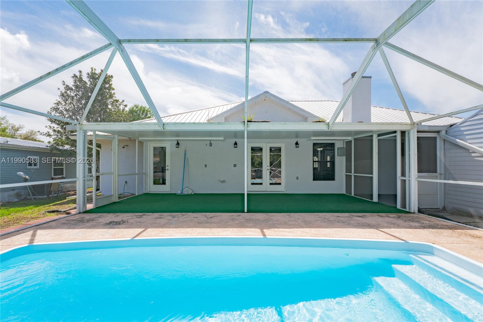 A swimming pool sits in front of a covered patio with a screened enclosure — 1063 Mayford Lake Rd, Moore Haven FL 33471, MOORE HAVEN, FL