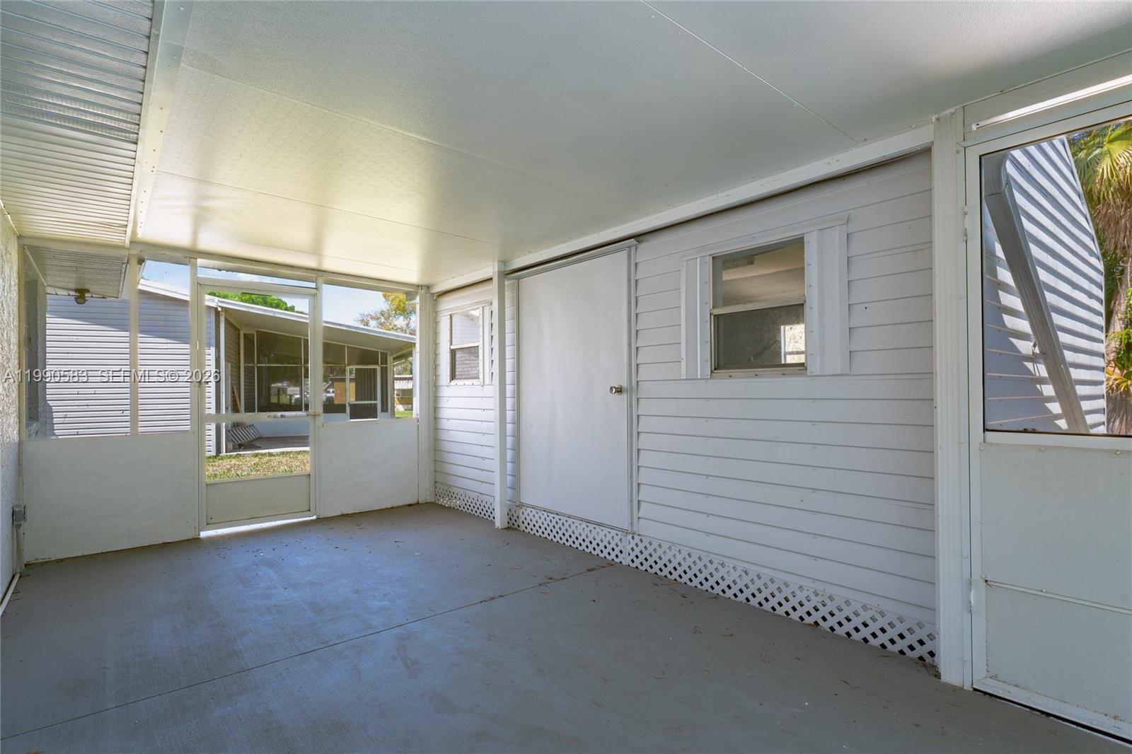 A covered patio features a concrete floor, white siding, a storage door, and screen enclosures — 1063 Mayford Lake Rd, Moore Haven FL 33471, MOORE HAVEN, FL