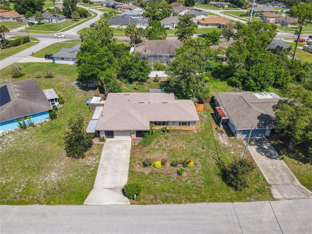 An aerial view shows a single-story house with a tan roof and concrete driveway — 1468 CORONET DRIVE, DELTONA, FL