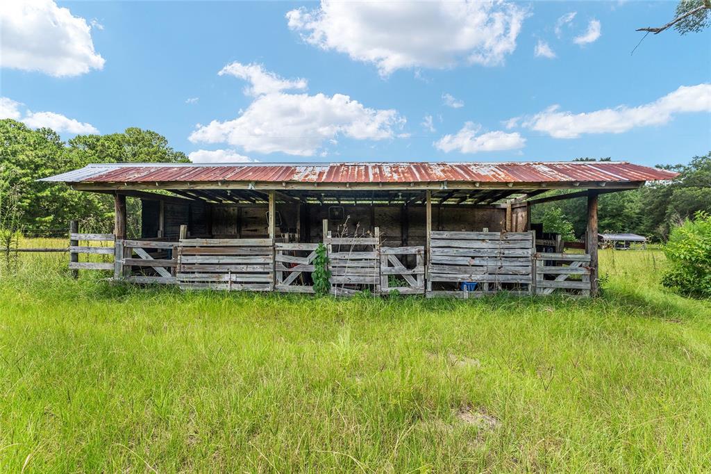 A weathered wooden barn with a rusted metal roof stands in a grassy field — 20104 NW 184TH TERRACE, HIGH SPRINGS, FL