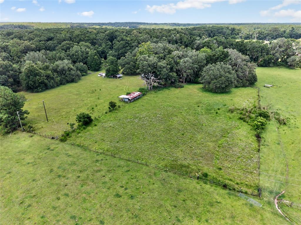 An aerial view shows a fenced pasture with a small shed and mature trees — 20104 NW 184TH TERRACE, HIGH SPRINGS, FL