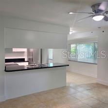A kitchen with a breakfast bar, dark countertops, and a ceiling fan in the dining area — 605 HILLPOINT WAY, BRANDON, FL