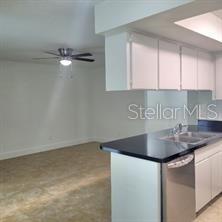 A kitchen with white cabinets and a black countertop overlooks an adjacent living area — 605 HILLPOINT WAY, BRANDON, FL