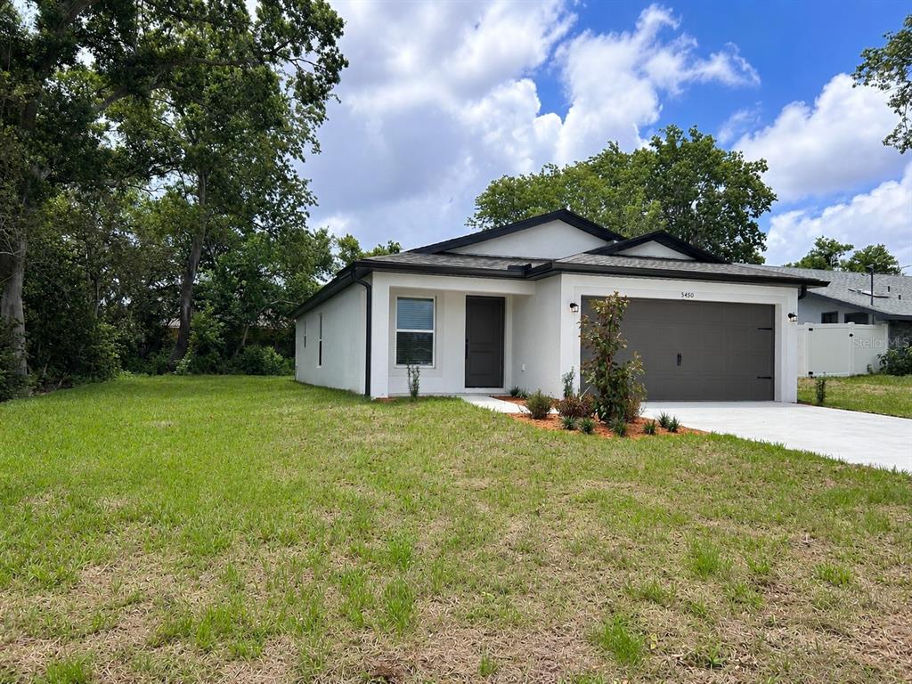 A single-story house with white stucco walls, a dark roof, and a two-car garage — 5450 PARNELL AVENUE, SPRING HILL, FL