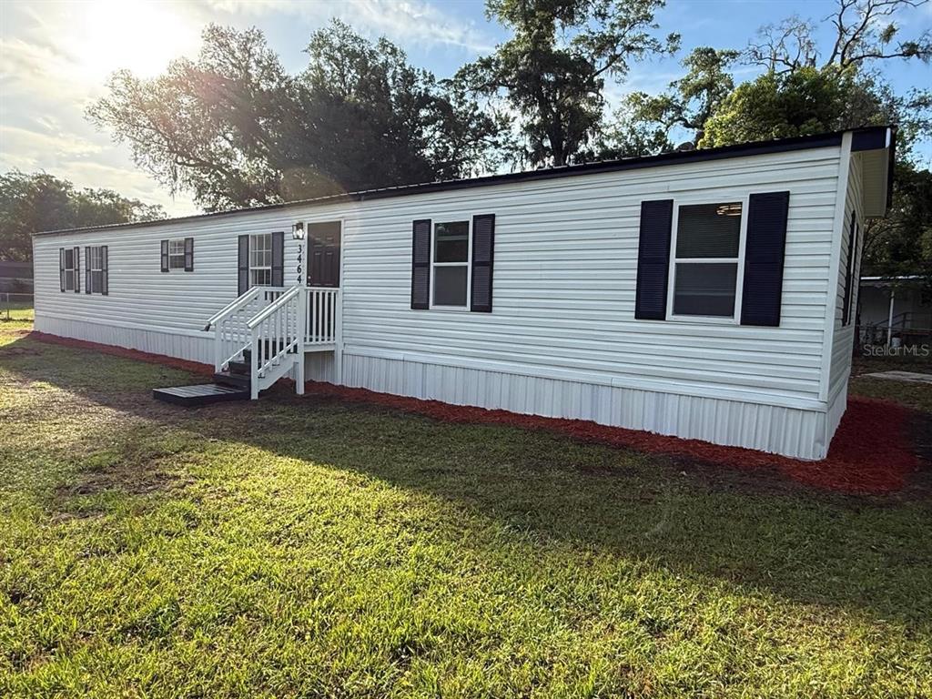 A white single-wide mobile home with black shutters sits on a grassy lot — 3464 SE 91ST PLACE, OCALA, FL