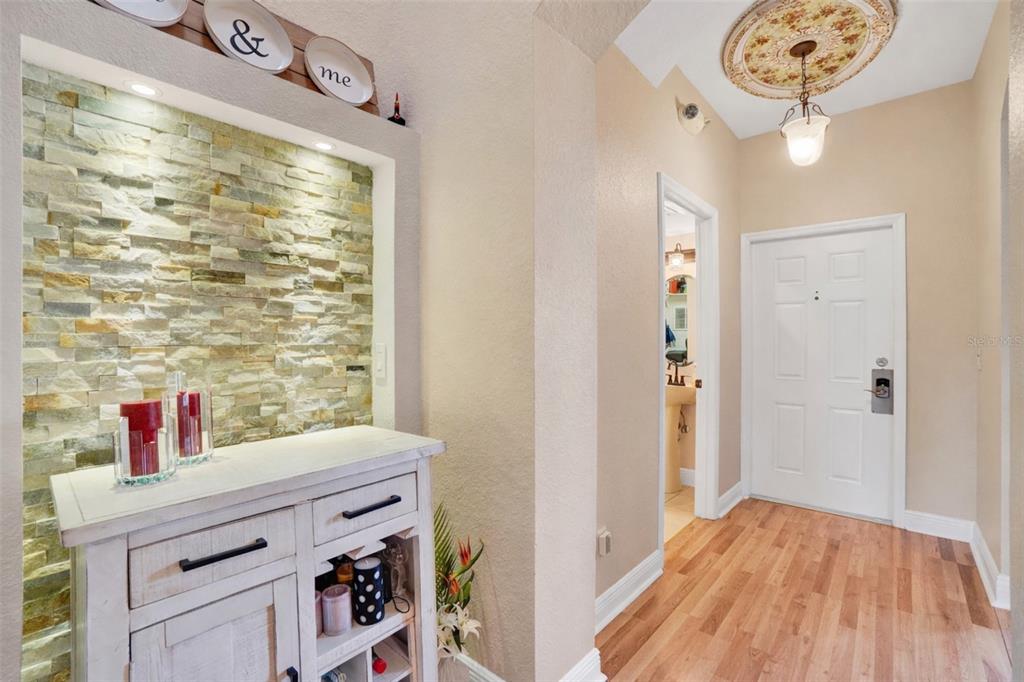 An entryway features a stone accent wall, a white cabinet, and a wood-look floor — 3326 CALABRIA AVENUE, DAVENPORT, FL