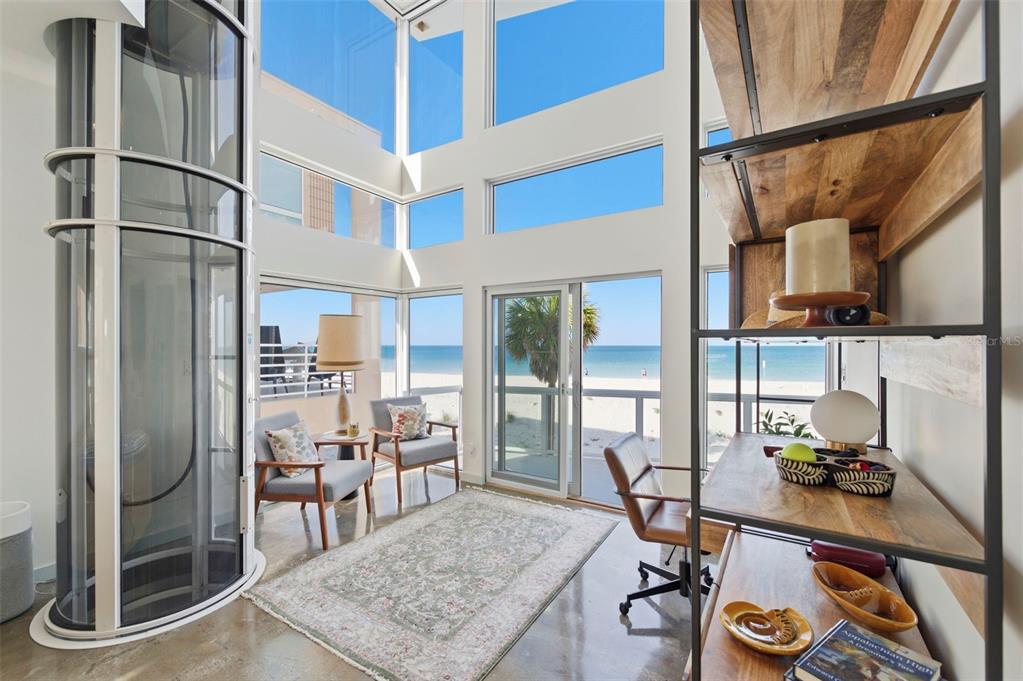 A bright room with a glass elevator, floor-to-ceiling windows, and a view of the beach — 8680 W GULF BOULEVARD, TREASURE ISLAND, FL