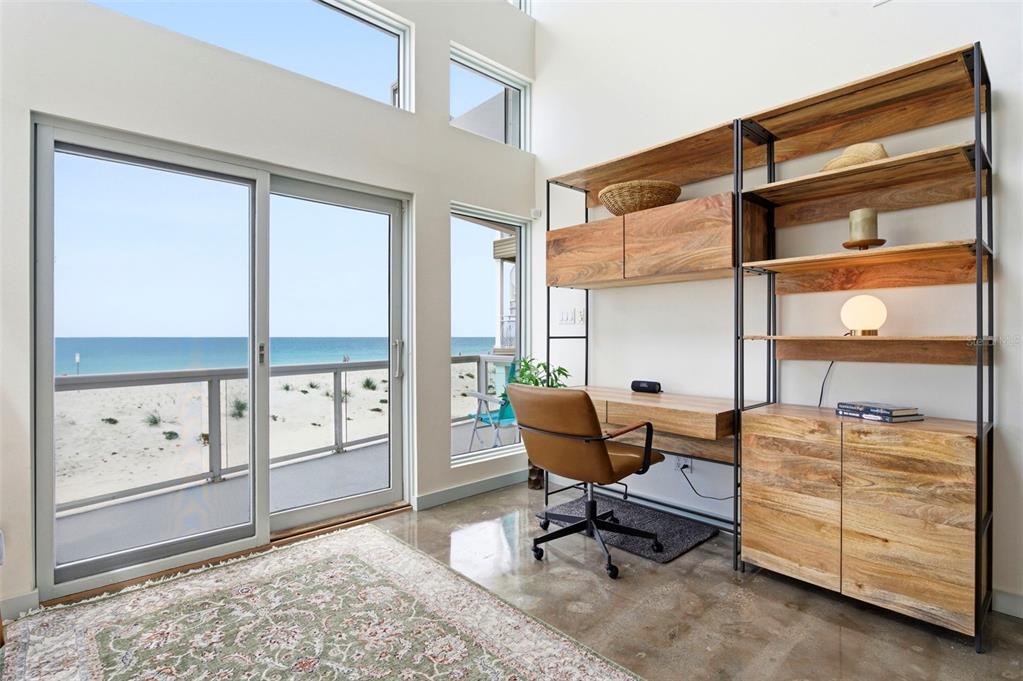A home office with a desk, shelving unit, and sliding glass doors overlooking the beach — 8680 W GULF BOULEVARD, TREASURE ISLAND, FL