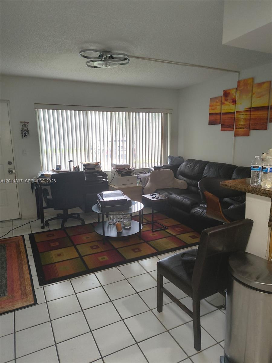 A living room features a black leather sofa, a desk, and a multi-paneled sunset artwork — 650 NW 86th Pl # 101, Miami FL 33126, MIAMI, FL