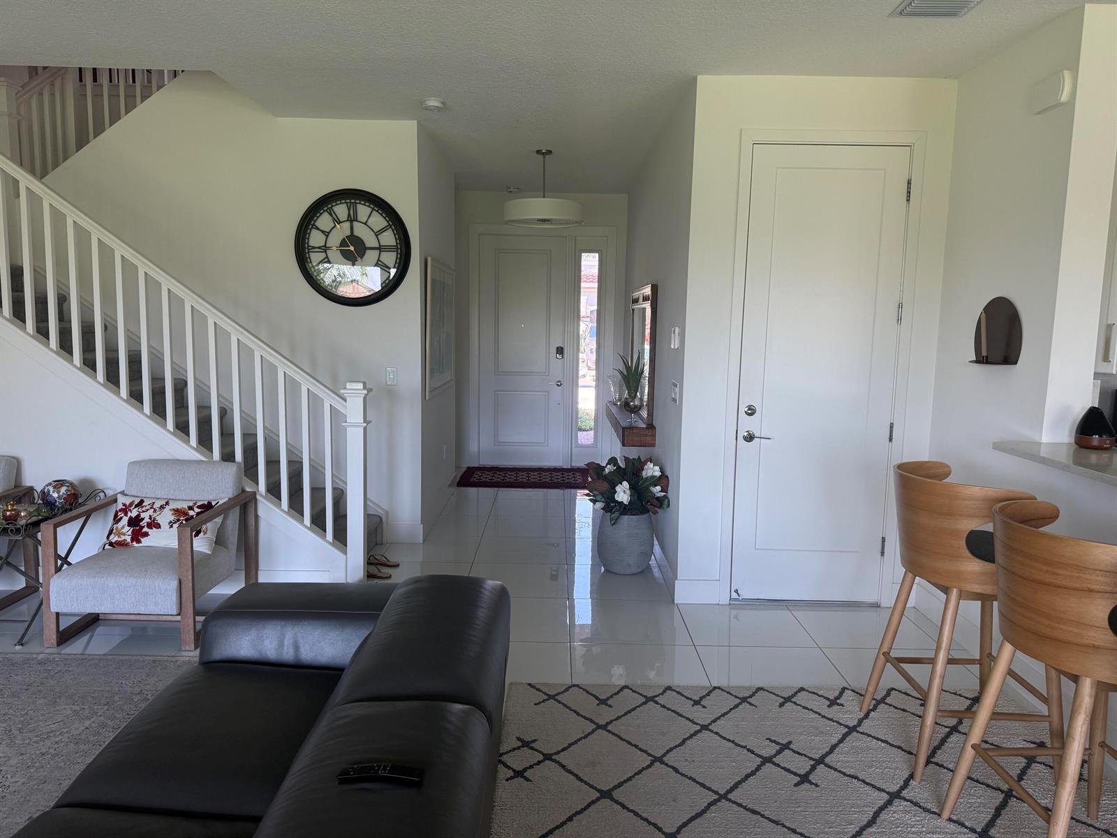 An entryway features white walls, tile flooring, a staircase, and a view of the front door — 9613 Highland Pointe Pass, Delray Beach FL 33446, DELRAY BEACH, FL