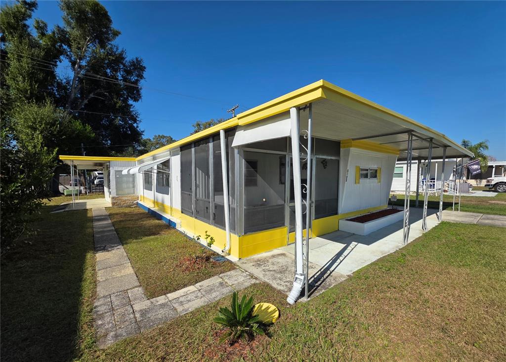 A single-story mobile home with a yellow trim, a screened-in porch, and a carport — 5105 CURRAN STREET, ZEPHYRHILLS, FL