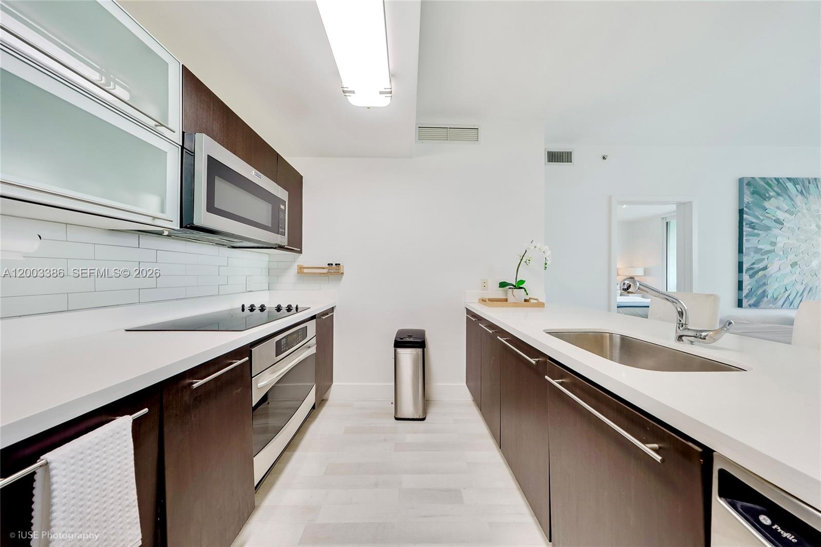 A modern galley kitchen features dark wood cabinets, white countertops, and stainless steel appliances — 90 SW 3rd St # 3109, Miami FL 33130, MIAMI, FL