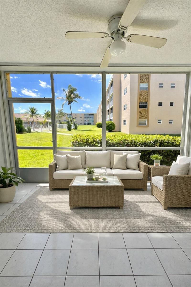A screened-in patio features wicker furniture, a neutral area rug, and a view of buildings — 202 SE 10th Street # 105, Dania Beach FL 33004, DANIA BEACH, FL