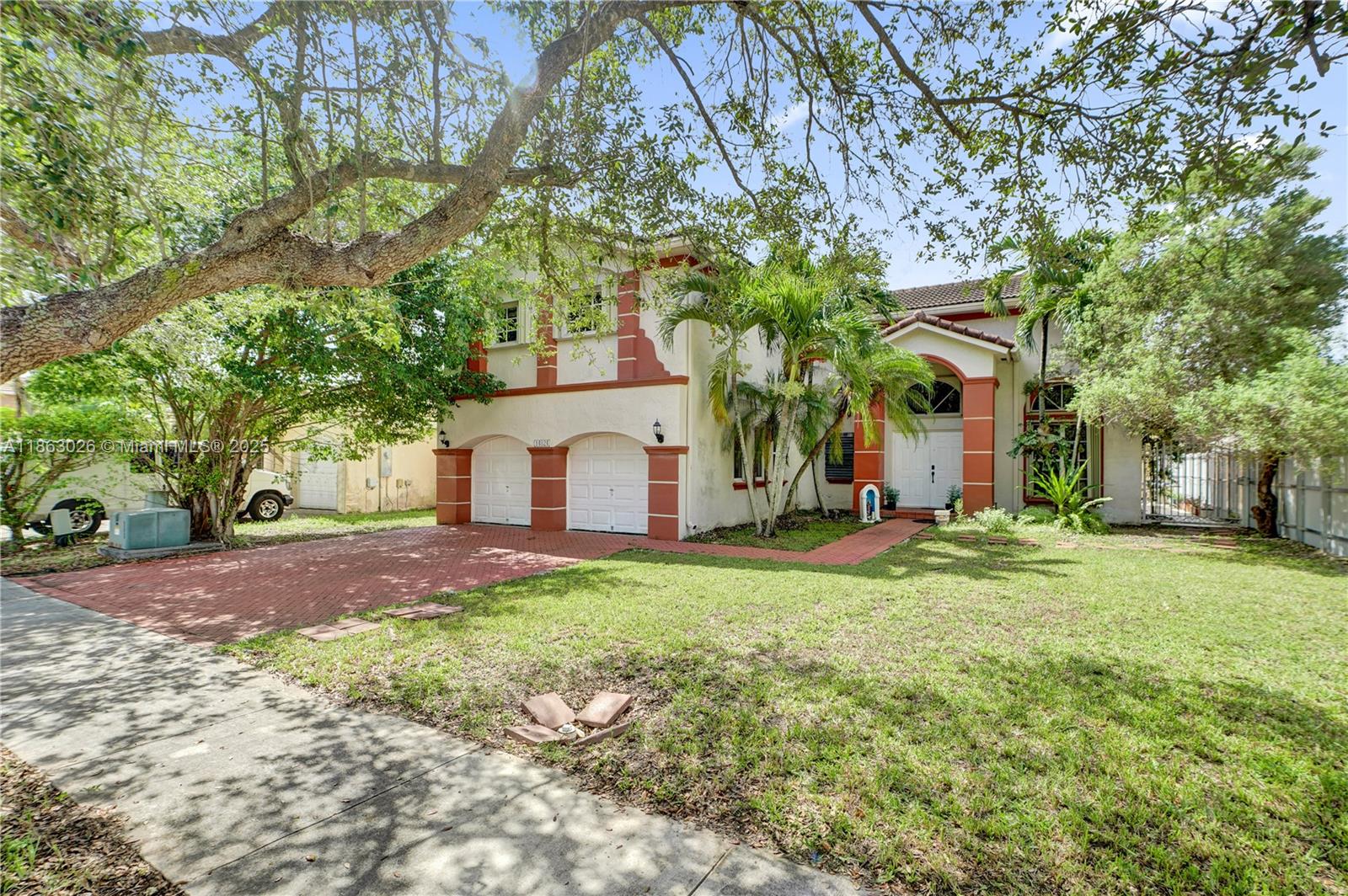A two-story house with a red-trimmed stucco facade, two garage doors, and a brick driveway — 14824 SW 180th St, Miami FL 33187, MIAMI, FL