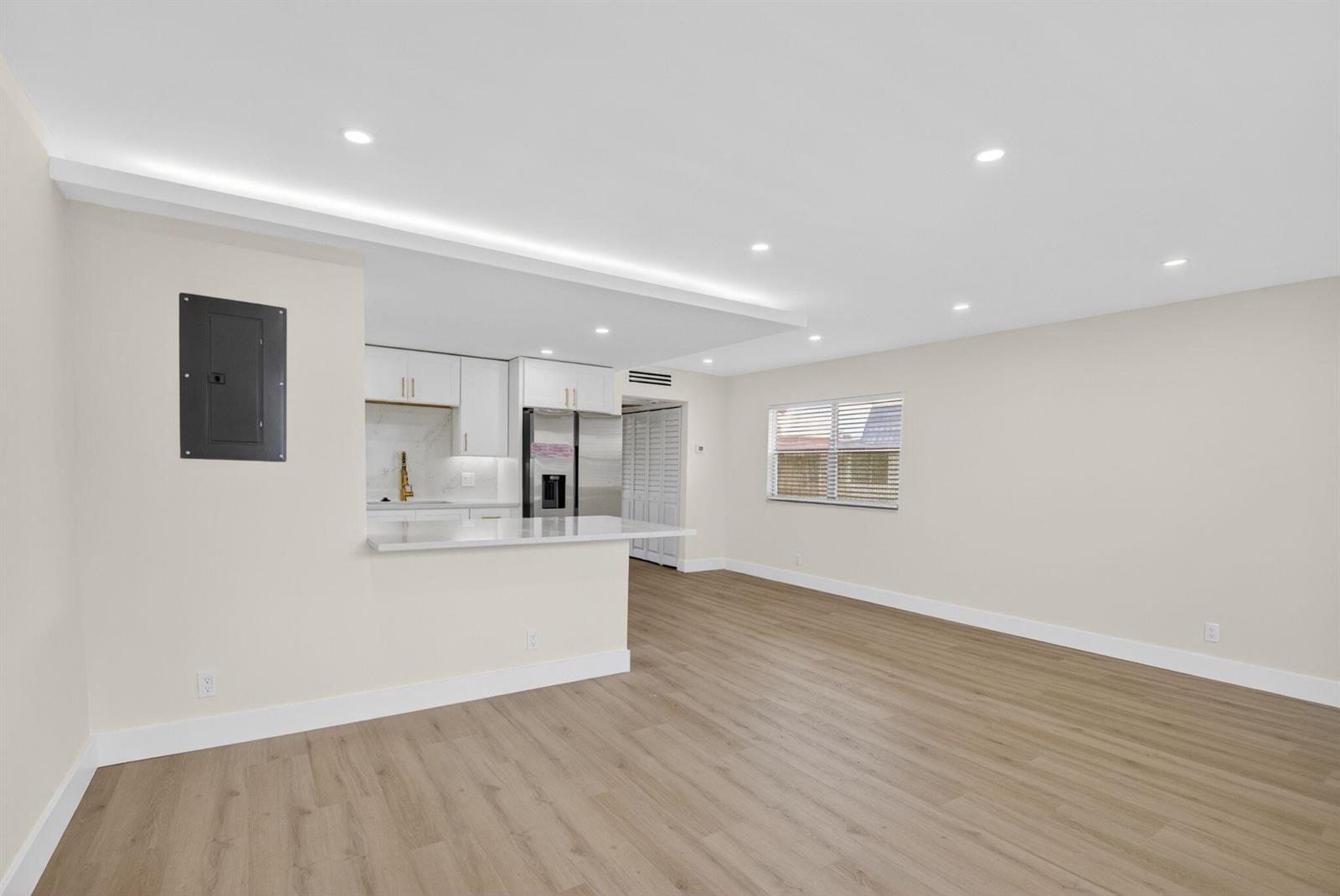 An open-concept living area features light wood-look flooring, recessed lighting, and a modern kitchen — 270 Brittany F, Delray Beach FL 33446, DELRAY BEACH, FL