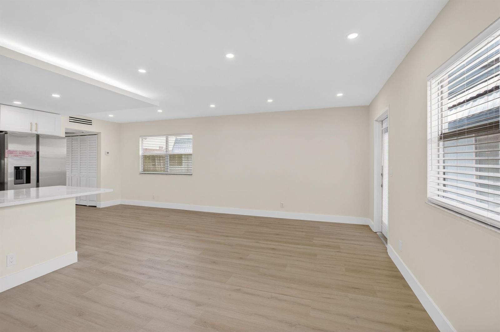 An open-concept living area features light wood-look flooring, recessed lighting, and a modern kitchen island — 270 Brittany F, Delray Beach FL 33446, DELRAY BEACH, FL