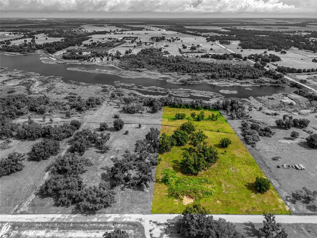 An aerial view shows a rectangular plot of green land bordering a river and road — 26217 39TH PLACE E, MYAKKA CITY, FL