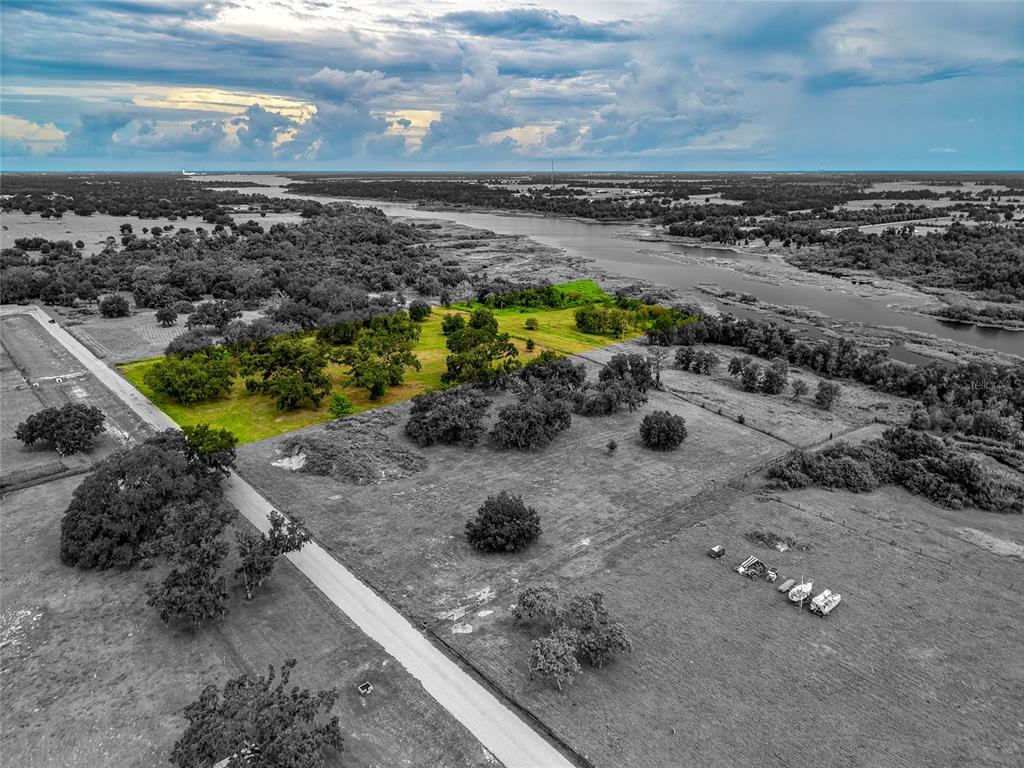 An aerial view shows a rural property with a highlighted green area near a river — 26217 39TH PLACE E, MYAKKA CITY, FL