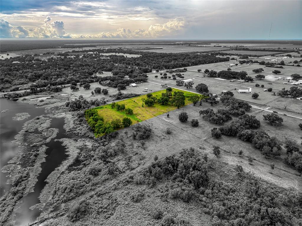 An aerial view shows a rectangular plot of green land highlighted against a grayscale landscape — 26217 39TH PLACE E, MYAKKA CITY, FL