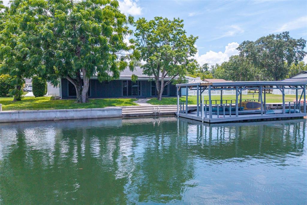 A waterfront house features a large tree, a concrete bulkhead, and a covered boat dock — 1218 SE 5TH AVENUE, CRYSTAL RIVER, FL