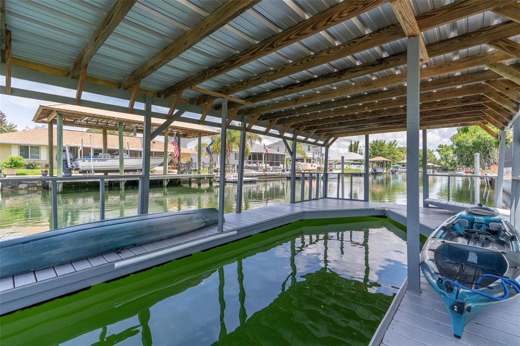 A covered boat dock with a slip, wooden decking, and two kayaks on the water — 1218 SE 5TH AVENUE, CRYSTAL RIVER, FL