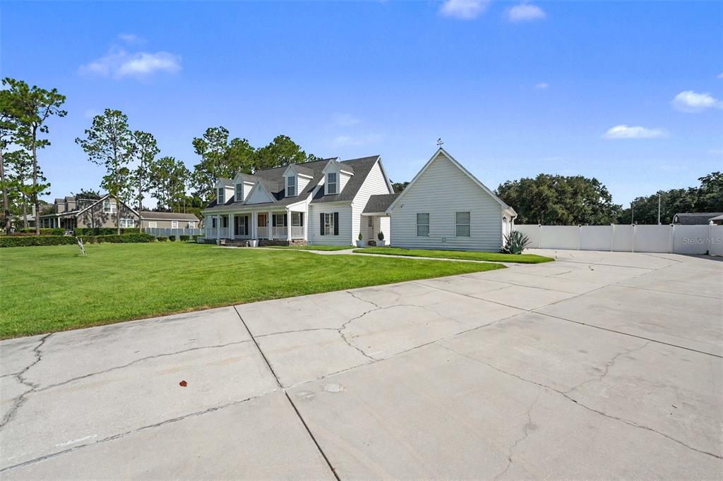 A white two-story house with a large concrete driveway and a grassy front lawn — 100 SYLVANA COURT, AUBURNDALE, FL