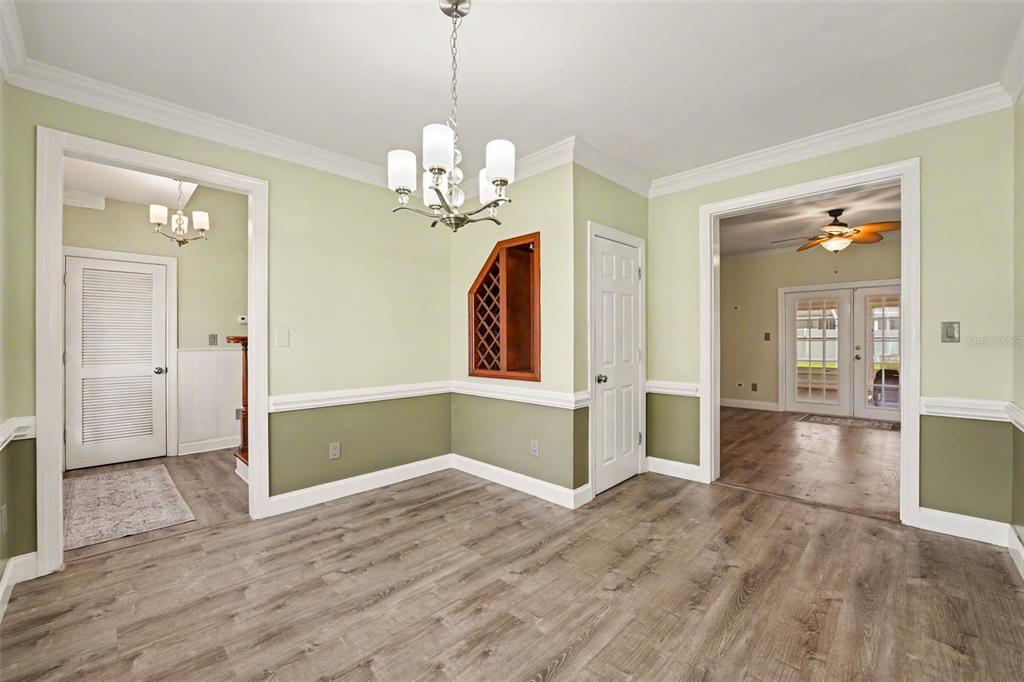 A dining room with two-tone green walls, a built-in wine rack, and wood-look flooring — 100 SYLVANA COURT, AUBURNDALE, FL
