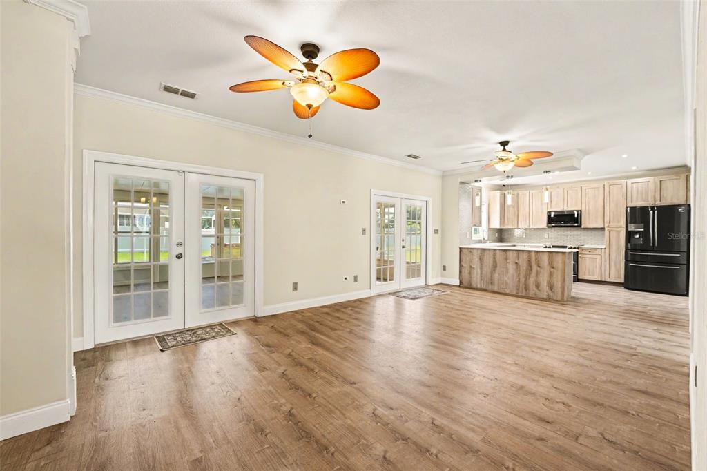 An open-concept living area features wood-look flooring, two ceiling fans, and a modern kitchen — 100 SYLVANA COURT, AUBURNDALE, FL