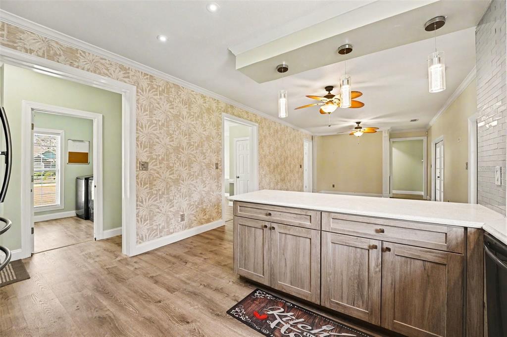 A kitchen with wood-look cabinets, a white countertop, and patterned wallpaper on the walls — 100 SYLVANA COURT, AUBURNDALE, FL