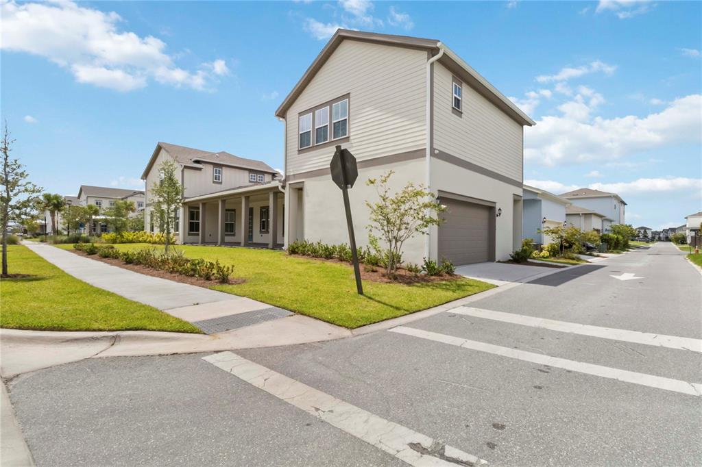 A two-story suburban house with a side-entry garage and a sidewalk along the street — 10388 BRAGG ALLEY, ORLANDO, FL