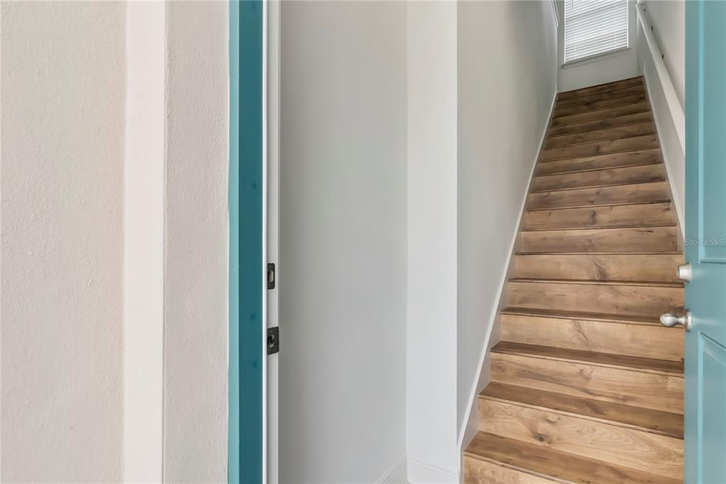 A staircase with wood-look treads leads upward next to a doorway with a teal frame — 10388 BRAGG ALLEY, ORLANDO, FL