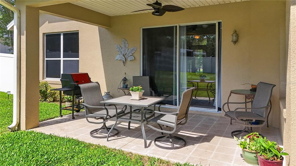 A covered patio features a dining set, a grill, and sliding glass doors to the home — 36806 WINFIELD COURT, GRAND ISLAND, FL