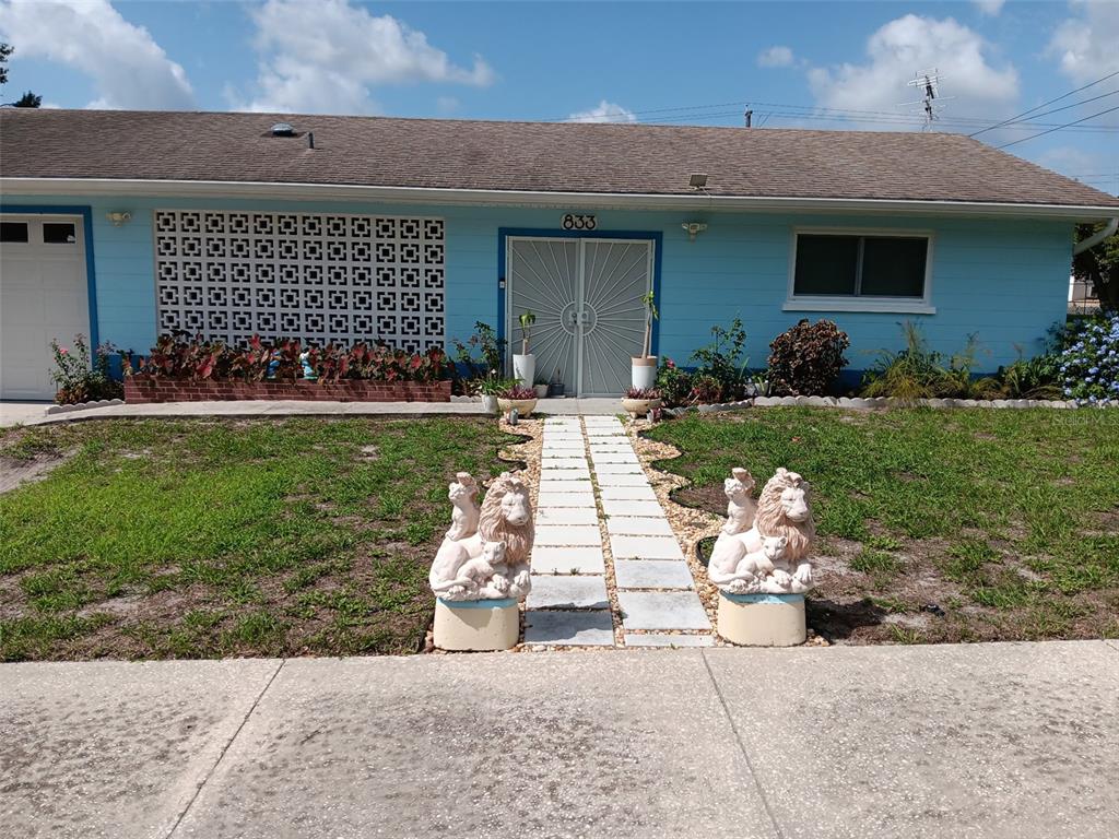 A light blue house features a decorative breeze block wall, double screen doors, and lion statues — 833 CHANNING ROAD, LAKELAND, FL