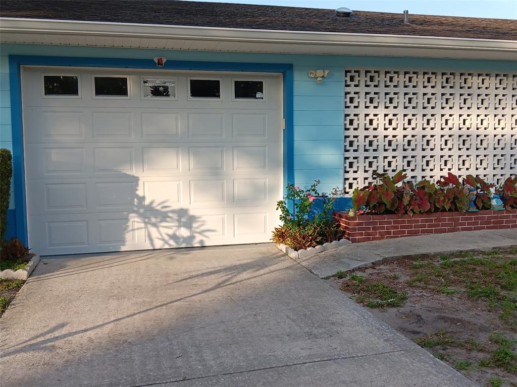 A white garage door is adjacent to a decorative breeze block wall and brick planter — 833 CHANNING ROAD, LAKELAND, FL