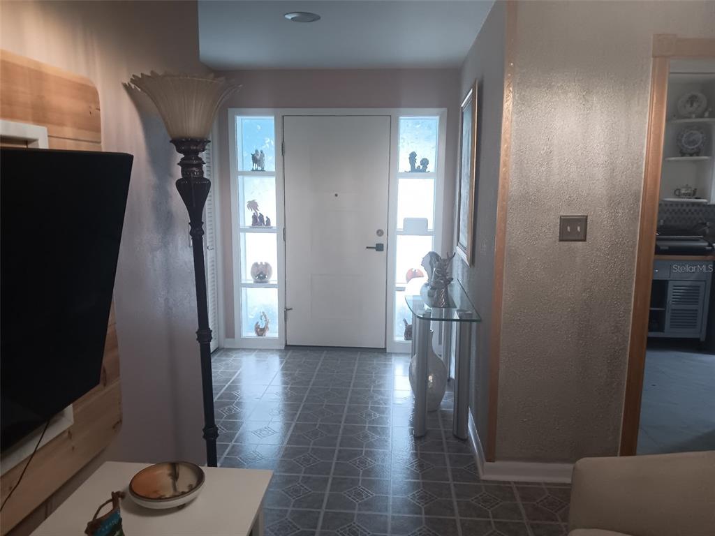 An entryway features a white front door with side windows, tile flooring, and a floor lamp — 833 CHANNING ROAD, LAKELAND, FL