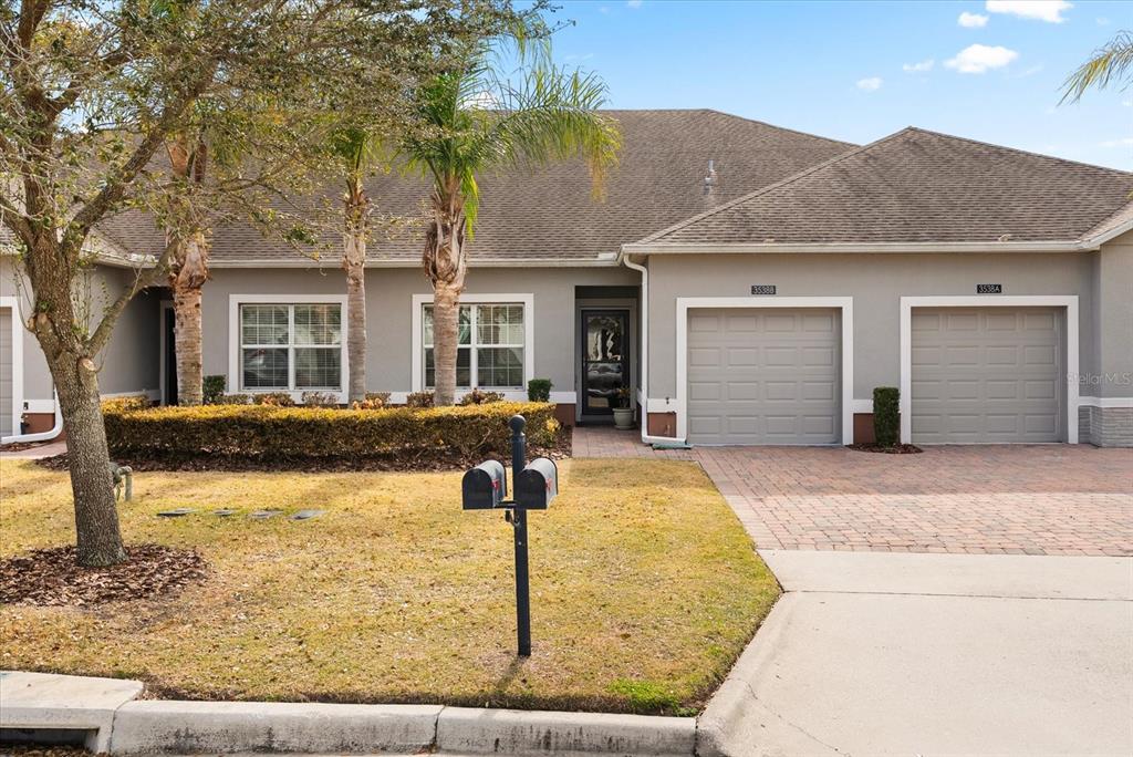 A single-story duplex with two garage doors, a paved driveway, and a front lawn — 3538 FAIRWATERS COURT UNIT B, CLERMONT, FL