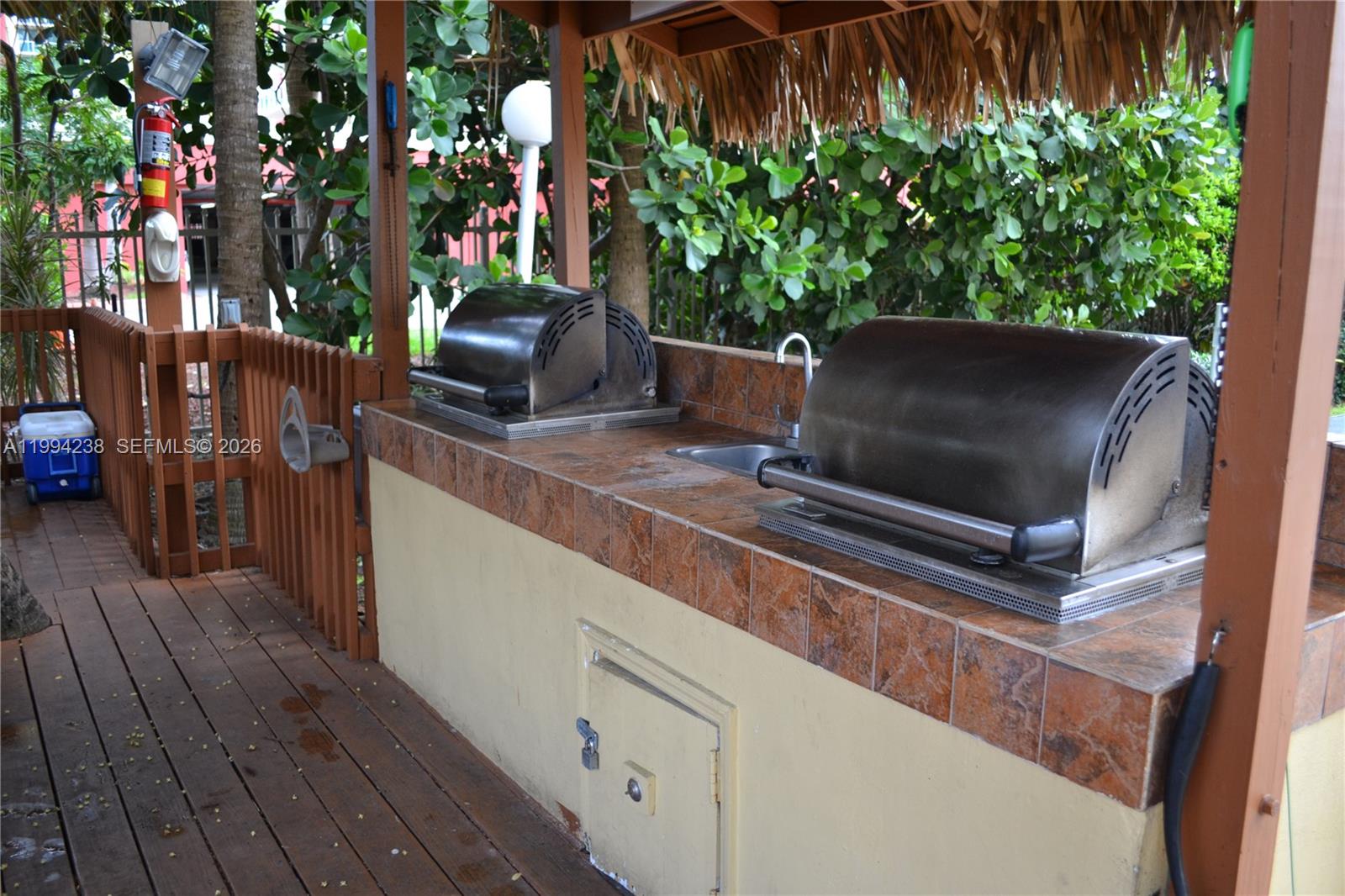An outdoor kitchen features two stainless steel grills and a sink set in tiled counters — SUNNY ISLES BEACH, FL