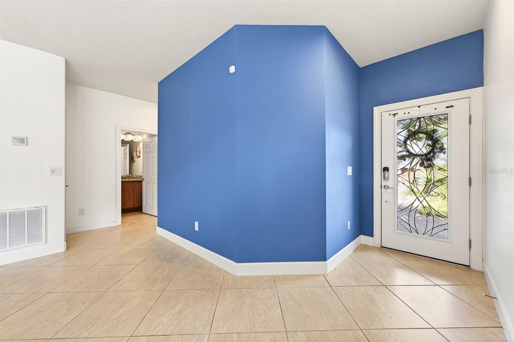 An entryway features a blue accent wall, tile flooring, and a white door with glass — 515 PAMPLONA PLACE, DAVENPORT, FL