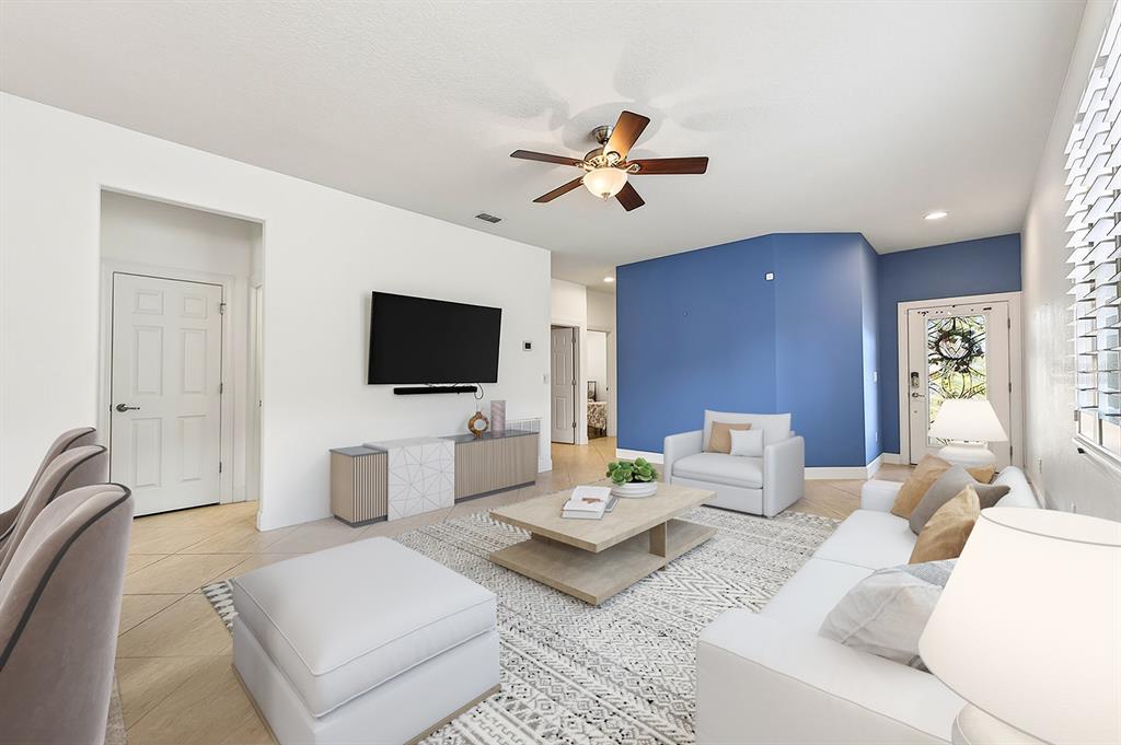 A living room features a blue accent wall, a white sofa, and a ceiling fan — 515 PAMPLONA PLACE, DAVENPORT, FL